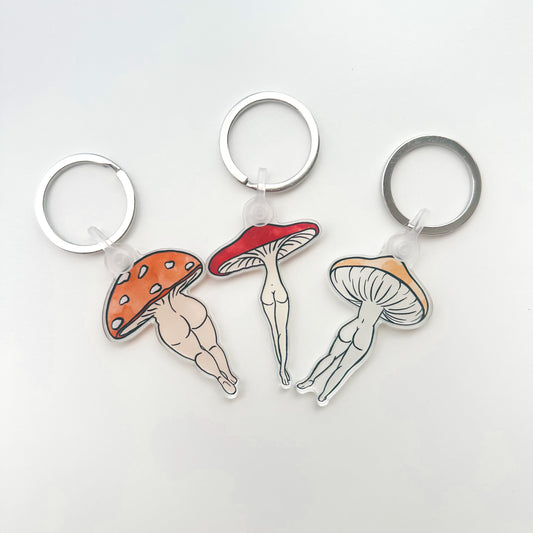 Three keychains with mushroom designs on a white background