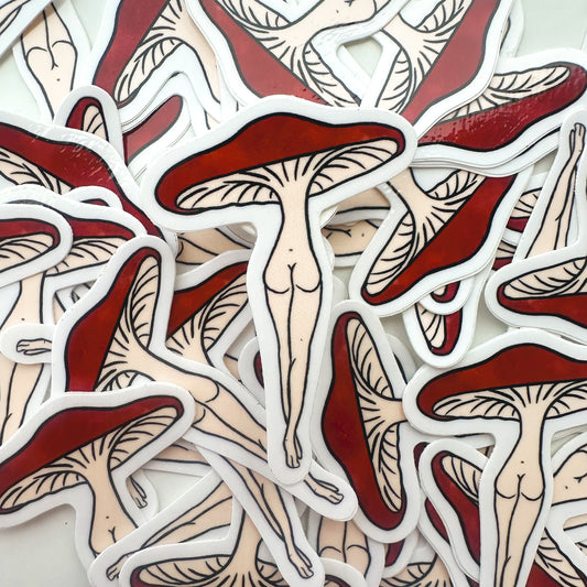 Stack of mushroom-shaped stickers with red caps and white stems on a light background