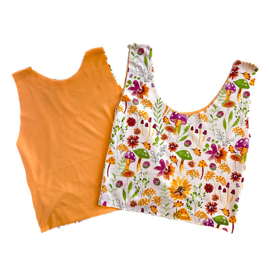 Two sleeveless tops, one with a solid orange color and another with a floral pattern on a light background, laid flat.